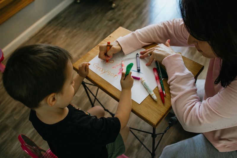 A caregiver and child drawing together