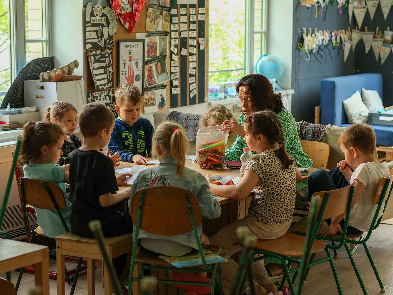 A caregiver leading a small group activity with children at a table
